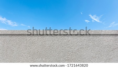 Concrete clean wall as border and blue sky with white clouds as background