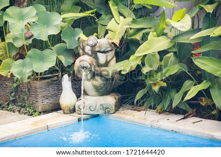 Stone statue on the edge of a swimming pool.
