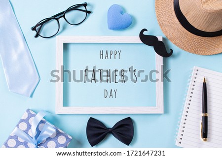 Happy fathers day concept. Top view of tie, beautiful gift box, hat, white picture frame with Happy father's day text on bright blue pastel background. Flat lay.