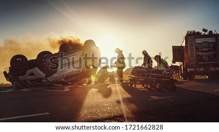 On the Car Crash Traffic Accident: Paramedics and Firefighters Rescue Injured Trapped Victims. Medics give First Aid to Female on Stretchers. Firemen Use Hydraulic Cutters Spreader to Open Vehicle Royalty-Free Stock Photo #1721662828