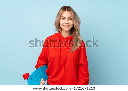 Teenager Russian girl isolated on blue background with a skate