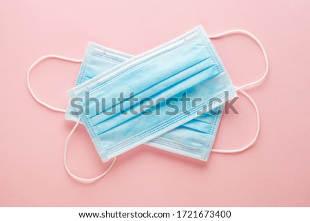 pair of blue medical surgical protective masks to cover nose and mouth on pastel pink background, top view, flat lay Royalty-Free Stock Photo #1721673400