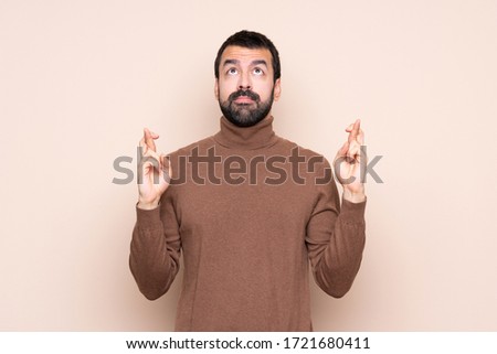 Man over isolated background with fingers crossing and wishing the best