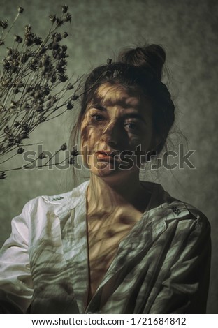 The shadow of dried flowers on the girl's face. Portrait of a beautiful girl