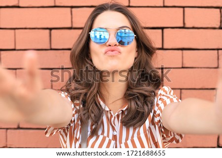 Optimistic smiling girl posing in front of old wall background.