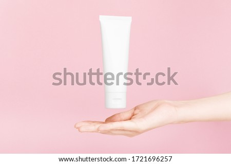 Female hand holding flacon for cream with golden cap. Plastic flacon for body lotion, toiletry. Container for cosmetics product. Skincare, advertising concept. Mockup style. Isolated on pink Royalty-Free Stock Photo #1721696257