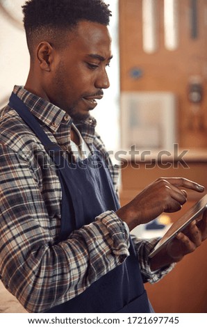 Male Craftsman In Carpentry Workshop For Bamboo Bicycles Using Digital Tablet