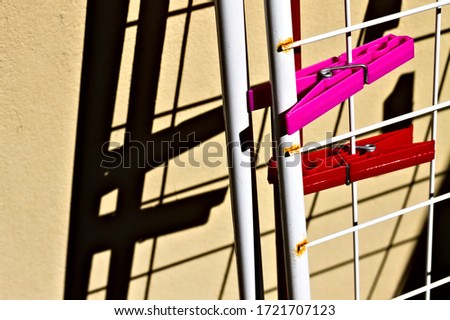 A pair of red and fuchsia clothespins attached to the clothehorse against the wall (Pesaro, Italy, Europe)