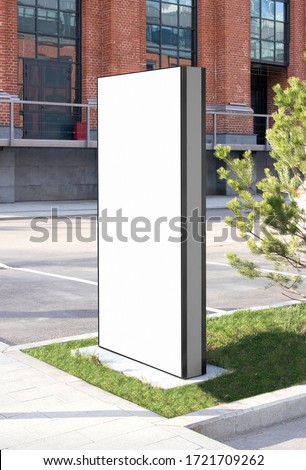 Blank white vertical pylon stand mockup brick building, side view. Empty information stand on street for advertise mock up. Clear vertical monitor or totem for affiche or ad mokcup template. Royalty-Free Stock Photo #1721709262