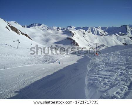 Beautiful almost empty ski slope with awesome view of snowy hills and another ski slopes in far distance. With chair lift crossing the picture.