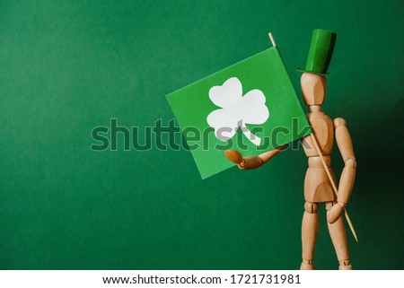 Wooden man in a hat with a green flag which depicts a clover. St. Patrick's Day.