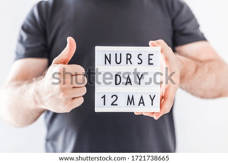 Nurse day concept. Man hands holding lightbox with text Nurse day 12 May thanking doctors, nurses and medical staff working in hospitals during coronavirus COVID-19 pandemics