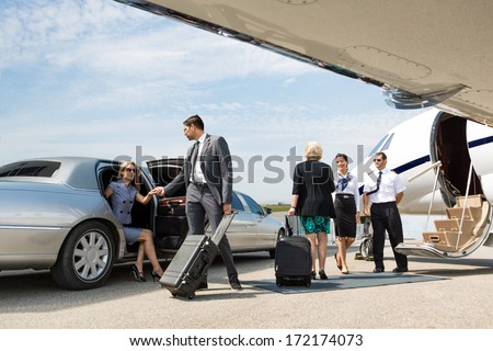 Business partners about to board private jet while airhostess and pilot greeting them Royalty-Free Stock Photo #172174073