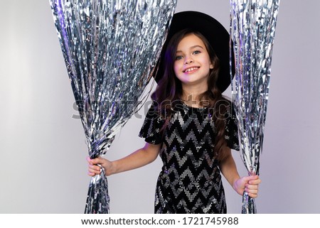 charming teen girl in a black hat and elegant dress posing on a birthday in the studio