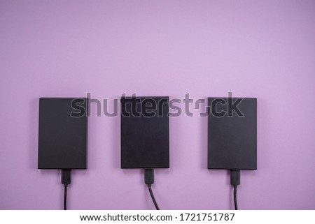 Three hard drives lie on the table against a lilac background. The view from the top. Information store. Data backup.