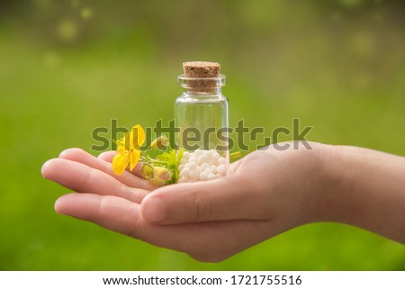 
container with homeopathic granules  on a young hand in the background of beautiful sunlight Royalty-Free Stock Photo #1721755516