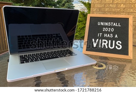 Photo of a felt letter board sign with a virus joke or meme for covid-19 / coronavirus pandemic on it. Placed beside a laptop when working from home. White letters. 