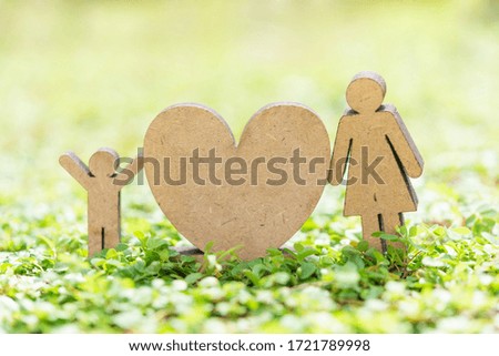 Happy Mother’s Day with heart icon,woman and kid model stand on fresh green grass in garden with copy space for text