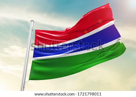 The Gambia national flag cloth fabric waving on the sky with beautiful sky - Image