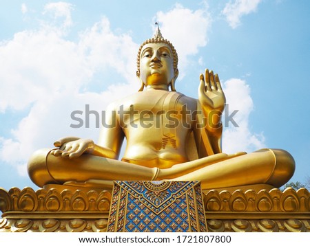 Big golden Buddha against blue sky background at Wat Pha Tang temple, Uthai Thani Province, Thailand.