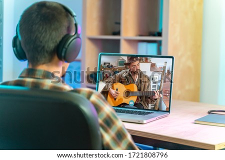 Coronavirus. Back view of man watching live video concert while staying at home. Close up of a man enjoying musical concert on laptop. Stay at home. Quarantine. Isolated. Royalty-Free Stock Photo #1721808796