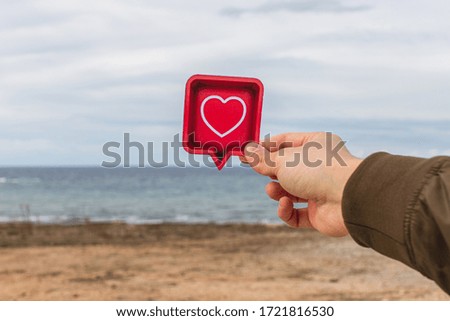 man holding paper heart near mediterranean sea
