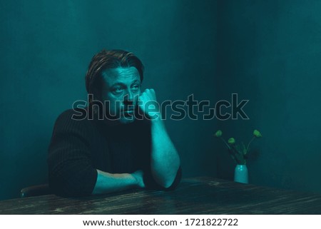 Bored man sitting at table in room in the night.