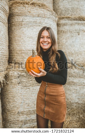 Young brunette woman holds a pumpkin in her hands for Halloween