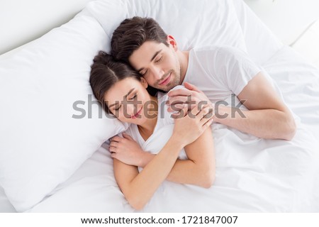 High angle above view photo charming cute lady husband guy couple lying comfortable sheets bed white blanket hugging joyful hold touch hands eyes closed wear pajama room indoors