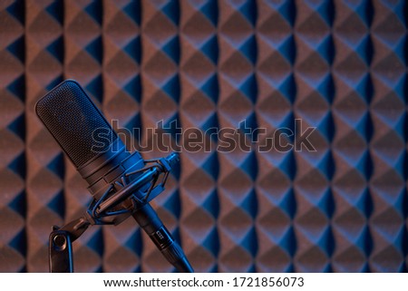 Studio condenser microphone on acoustic foam panel background with copy space on right