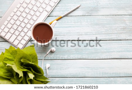 light blue wooden table with smartphone with blank screen mockup, laptop computer, cup of coffee and supplies. Top view with copy space, flat lay.