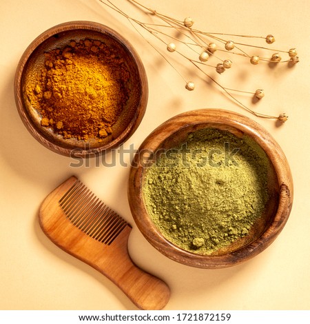 Henna powder in a wooden bowl and a wooden comb on a beige background top view. Natural hair care. Henna hair dye.