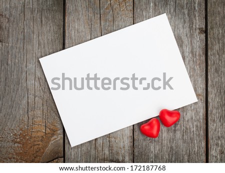 Valentine's day blank gift card and red candy hearts on wooden background