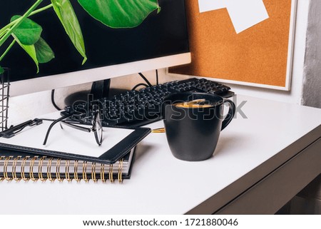 Stylish workspace with computer desktop, keybord, cup of coffee, office supplies, houseplant and clipboard at home or studio. Selective focus. Work from home concept.