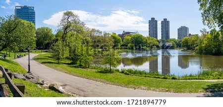 Central park in New York city near pond on a warm sunny day surrounded with skyscrapers