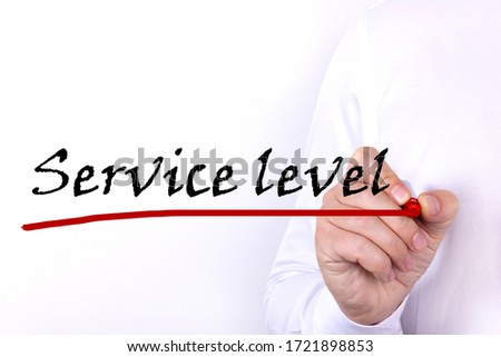 A person writes text, a word, the phrase Service Level with marker on a light background. Business concept.