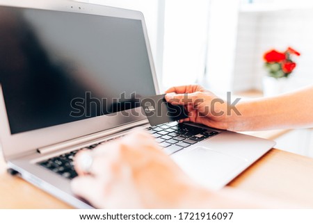 Woman holding black credit card on laptop. Online shopping, stay at home concept.
