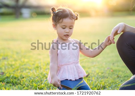 Adorable girl sitting at park holding her mother's hand. Mother day concept.