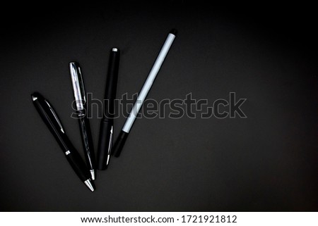four Traditional black and gray Pens isolated against a black background. Space for text, close up