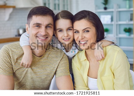 Happy smiling cheerful family hugging close-up in a living room.