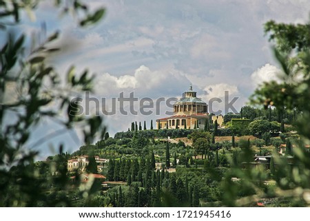 View of Tuscany with a domed building on top of a hill in a residential area full of cypresses and olive trees