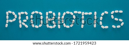 top view of probiotics lettering made of pills on blue background, panoramic orientation