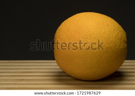 Three fresh orange on circle wood tray with dark background