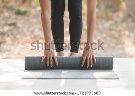 close-up of attractive young woman folding blue yoga or fitness mat after working out at home. calmness and relax, female happiness.Horizontal, blurred background. healthy life, keep fit concepts.