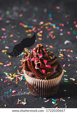 Chocolate cacao cupcakes with sprinkles and mustache, fathers day concept,  copy space on dark background, vertical