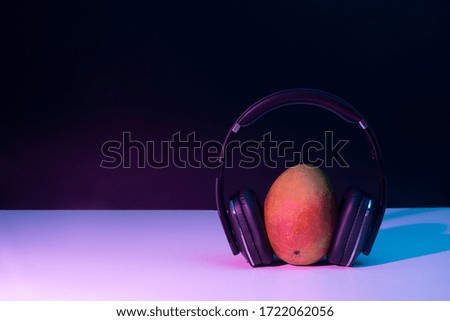 Fruit listening to music with headphones on on a black background with disco lights