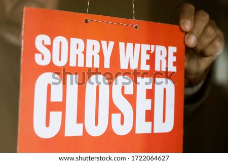 Business store owner turning closed sign at glass shop doorway