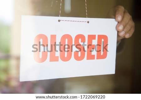 Business store owner turning closed sign at glass shop doorway