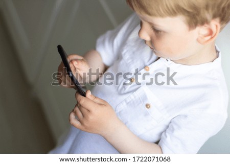 the child is holding a phone in his hand with a black screen. Communication via video communication.