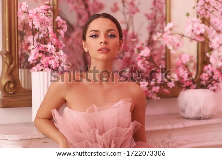 Closeup breast up portrait of elegant beautiful woman with makeup and pony tail hair in evening dress. Fashionable photo in pink colors